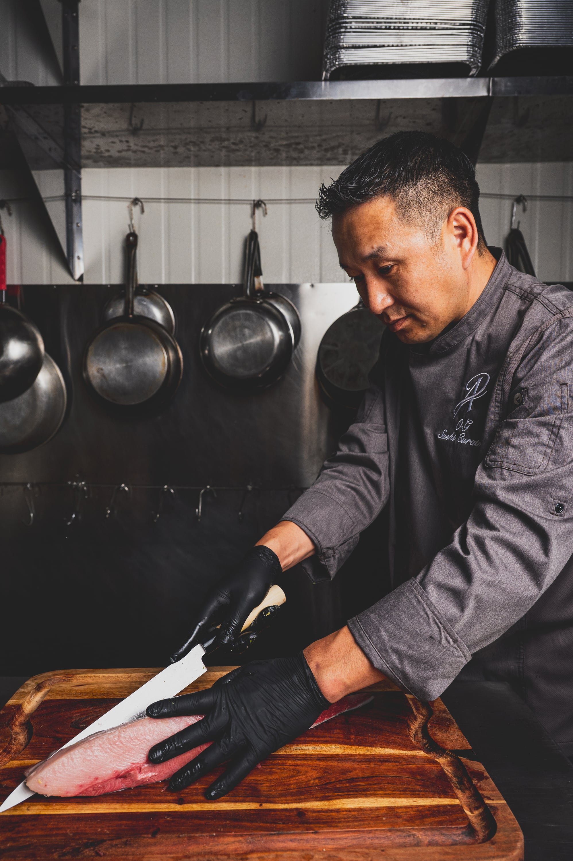 Chef carefully cutting fresh fish for sushi catering