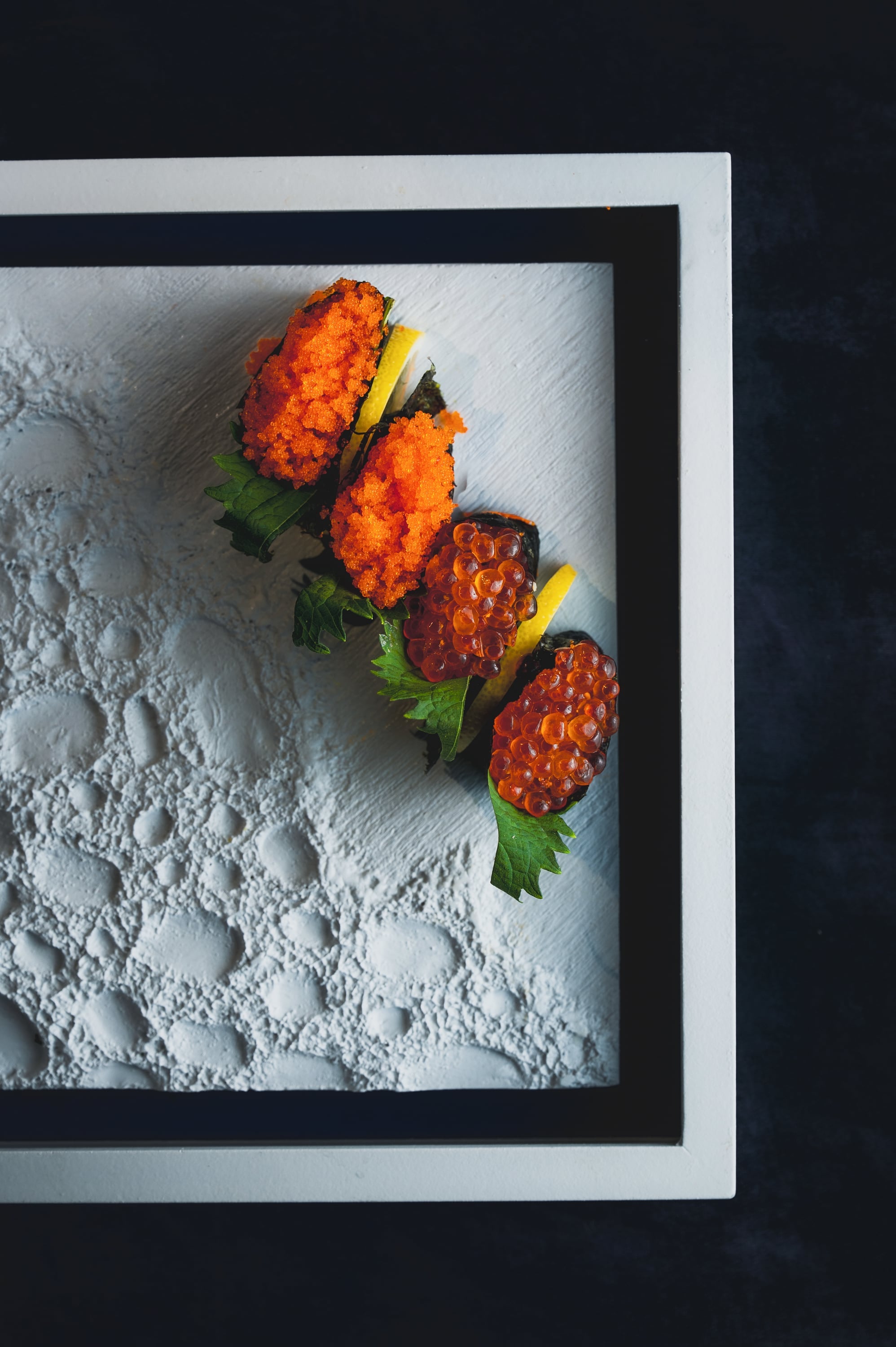 Tobiko and ikura gunkan nigiri arranged on white plate